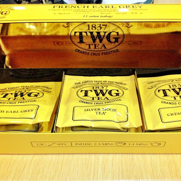 three packages of twg tea sitting inside of a metal case