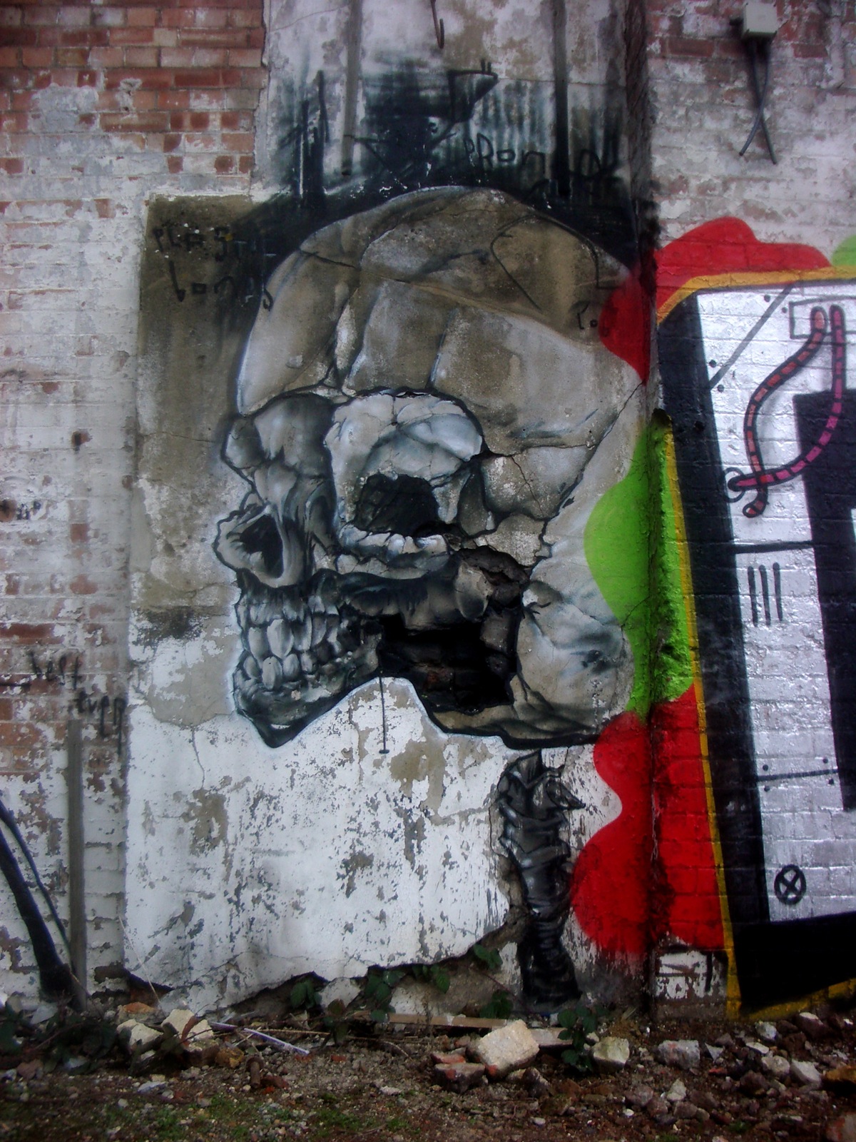 a painting on a brick wall of a skull and a cross