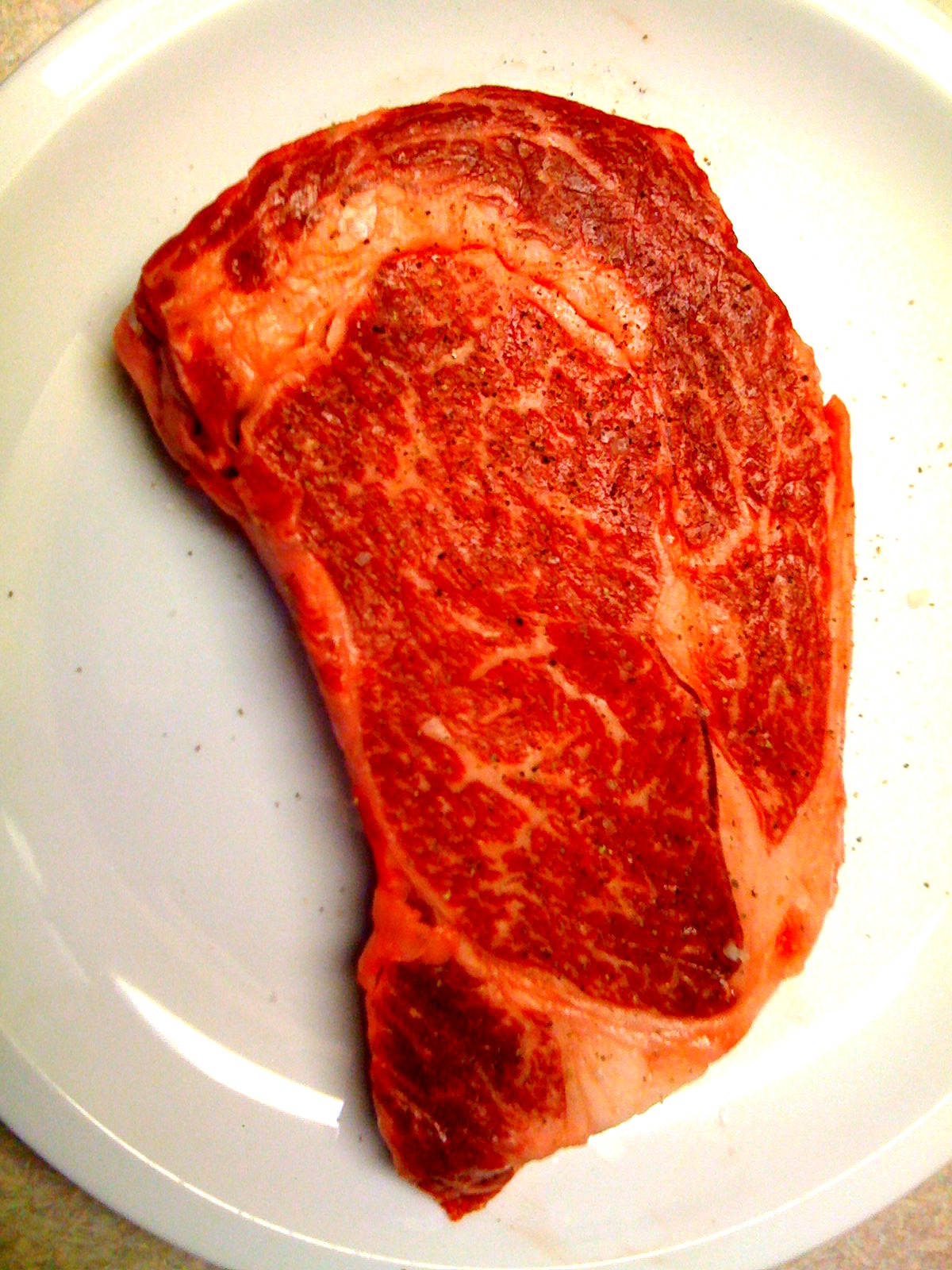 raw steak on plate with condiments on counter