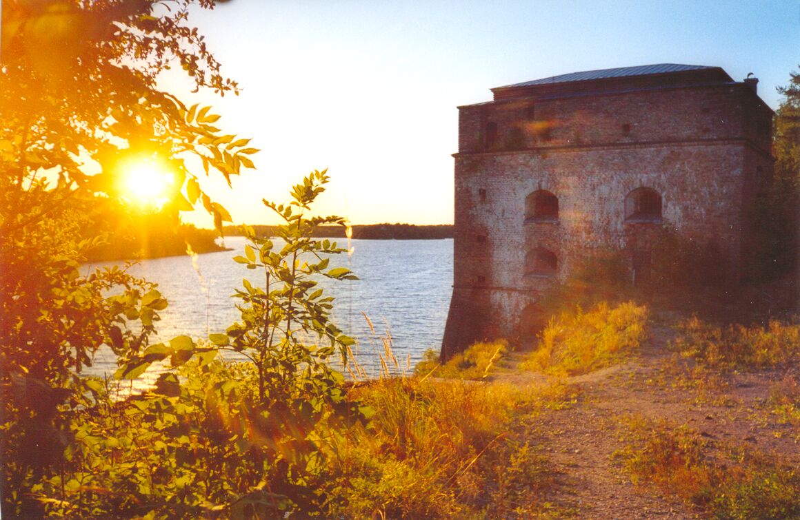 the sun shines brightly on an old brick tower near a river