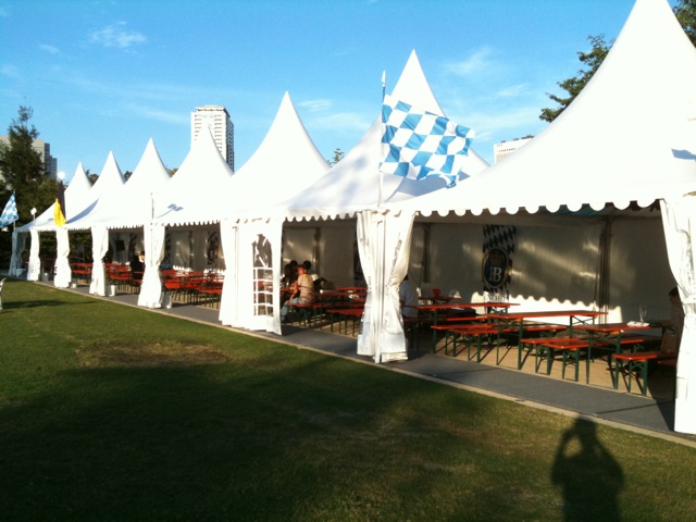 the large white tents have tables and chairs underneath them