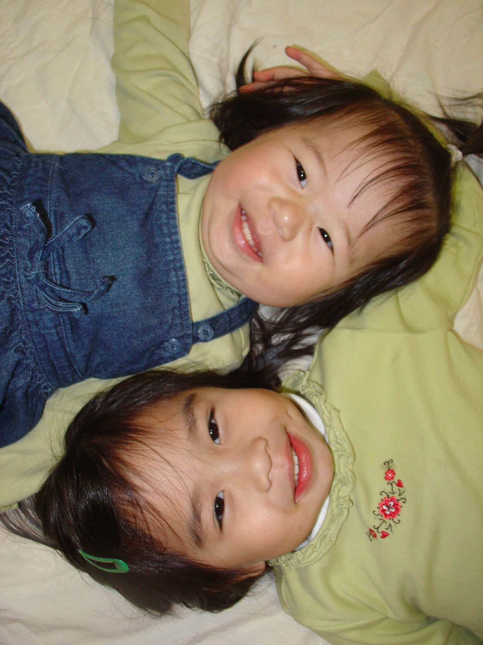 two asian girls laying on top of a bed