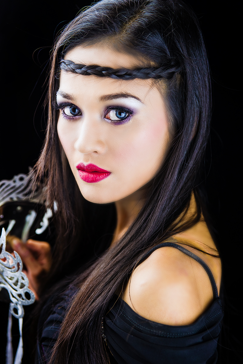 a woman with long black hair wearing a mask and red lipstick