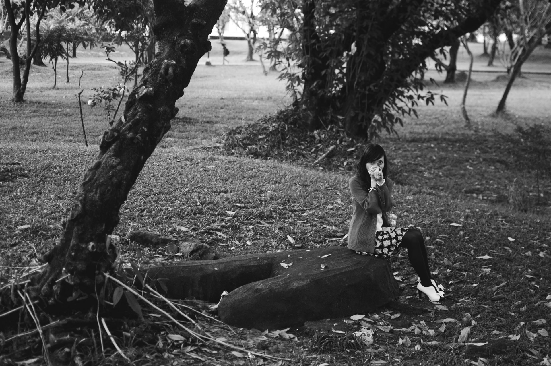 the woman is sitting on top of a fallen tree