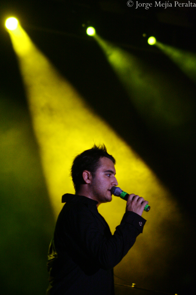a man with a toothbrush in his mouth standing in front of bright yellow spotlights