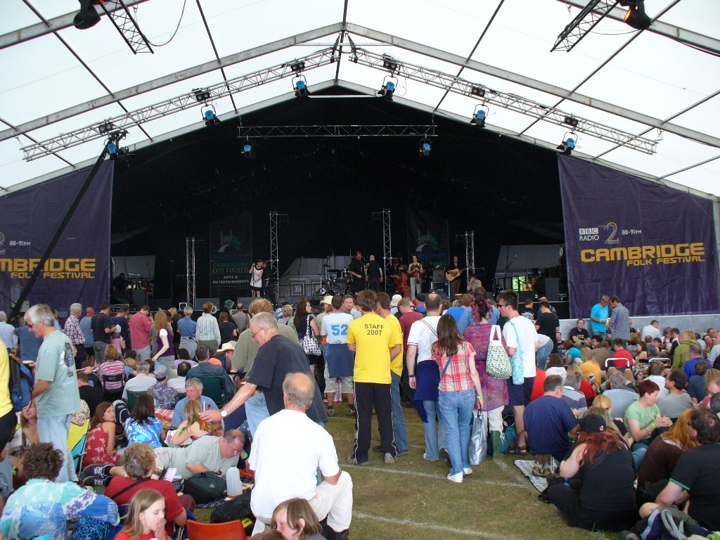 some people are standing near a stage and many are sitting down