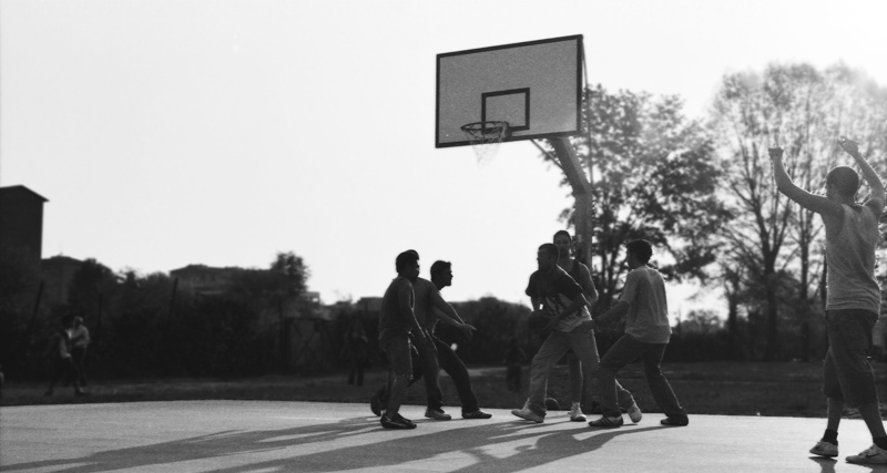 a group of people standing around in front of a basketball hoop
