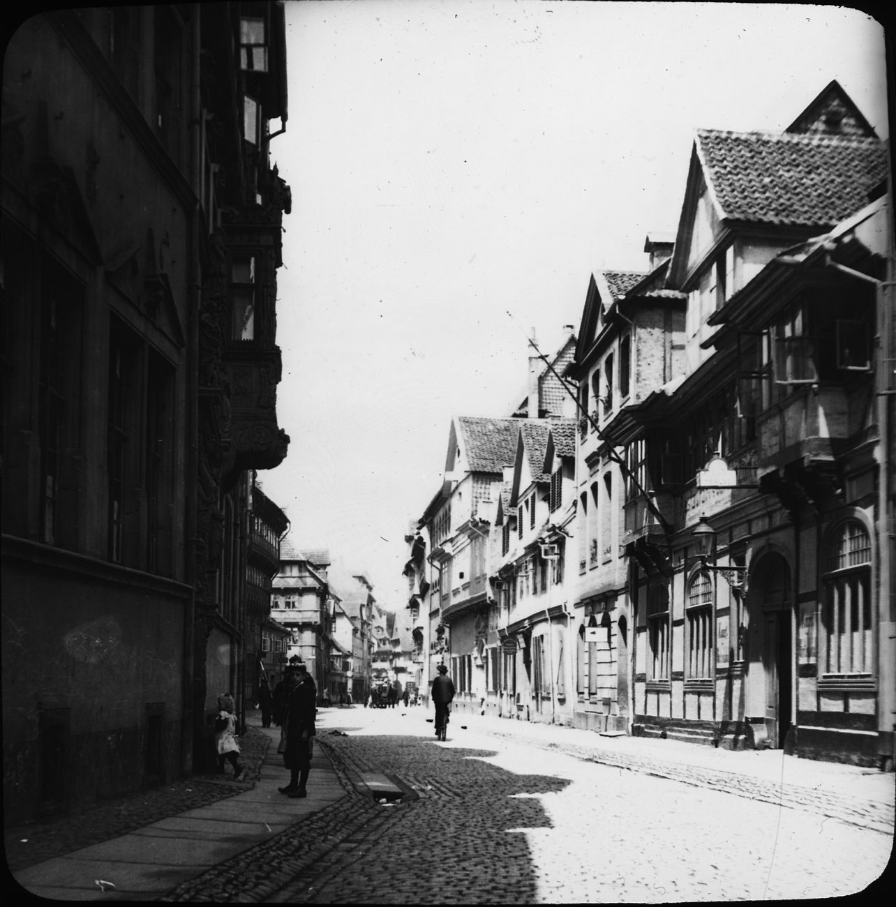 a vintage black and white po of a cobblestone street with buildings on both sides