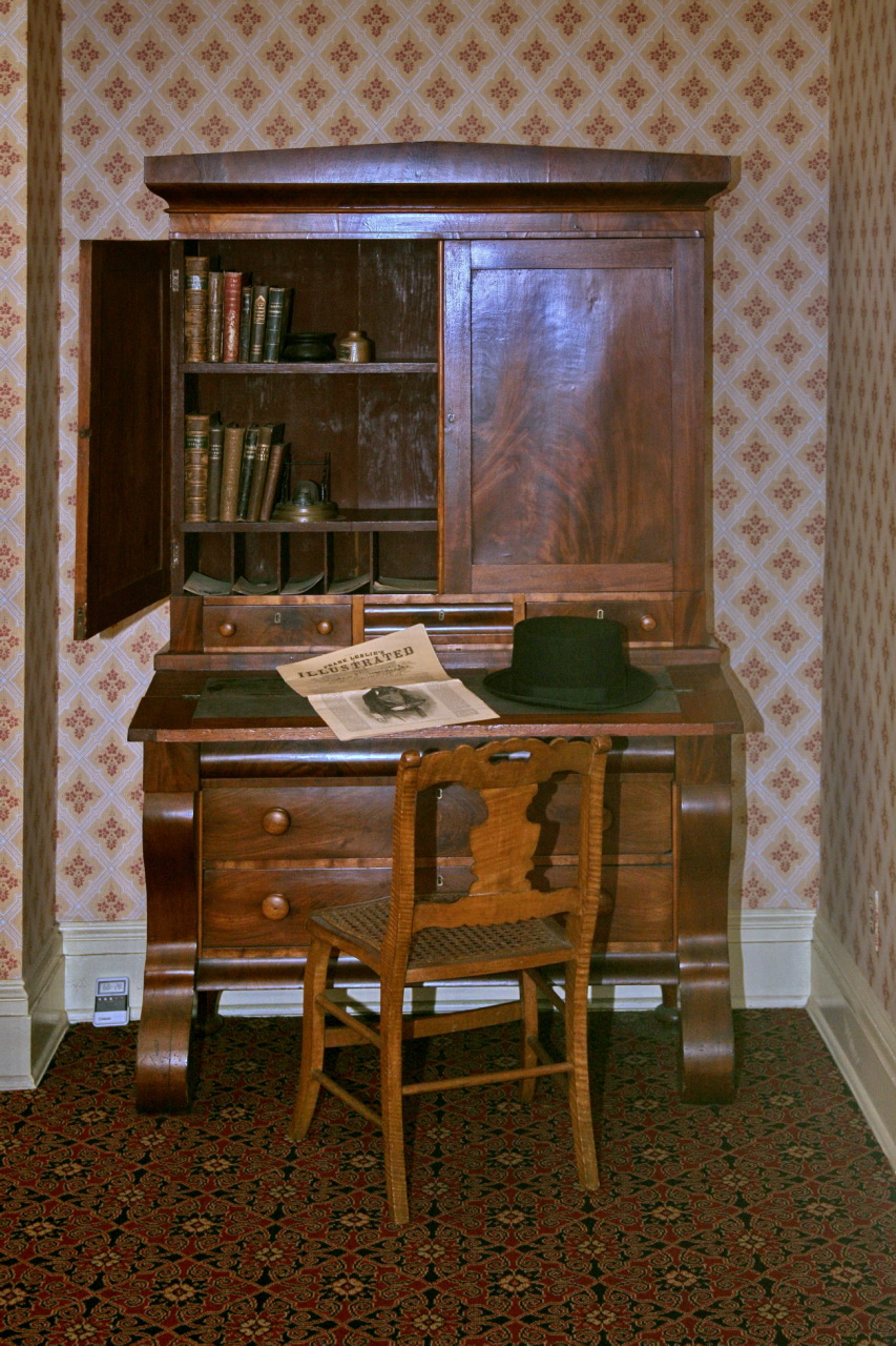 an old desk has a wooden chair, bookshelf and bookcase