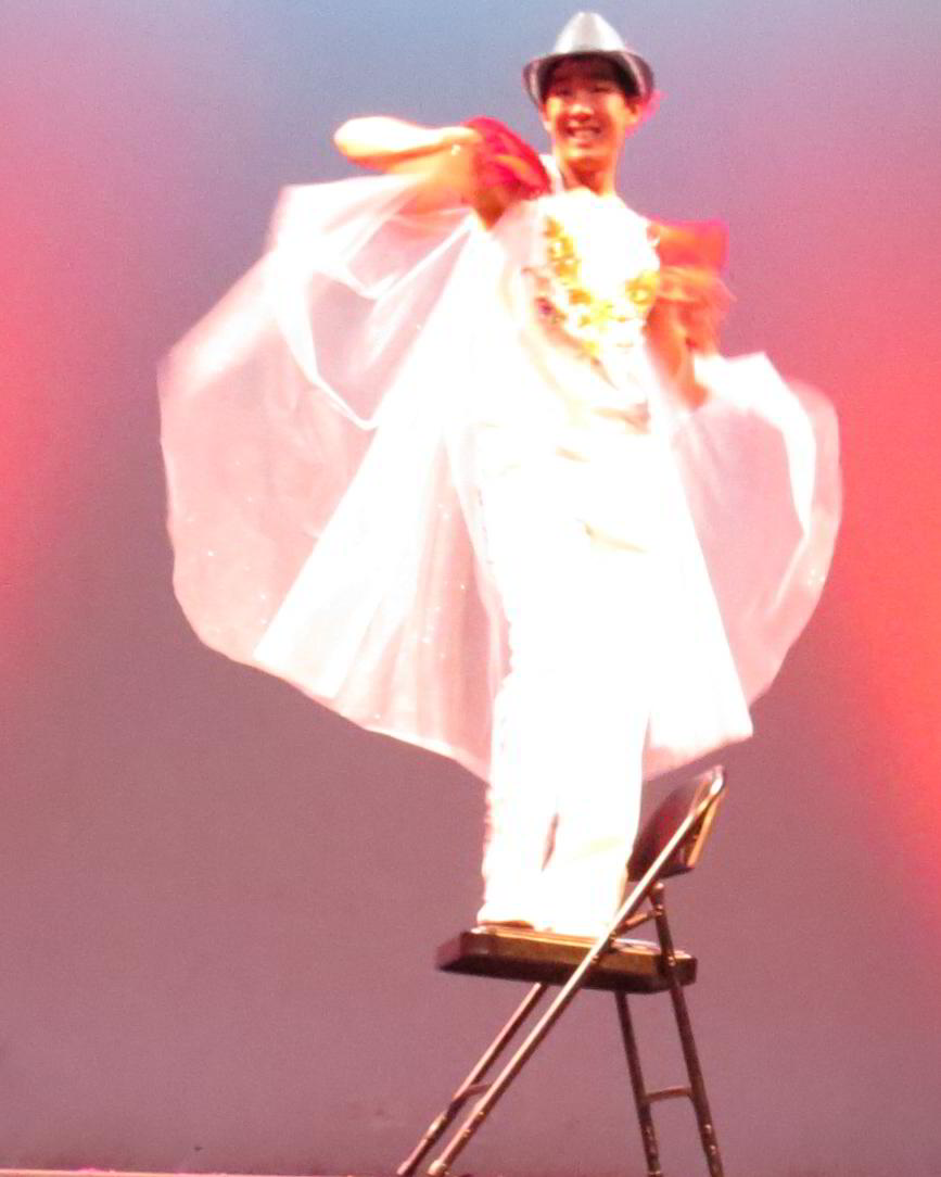 a man standing on top of a stool with a white cloth wrapped around his body