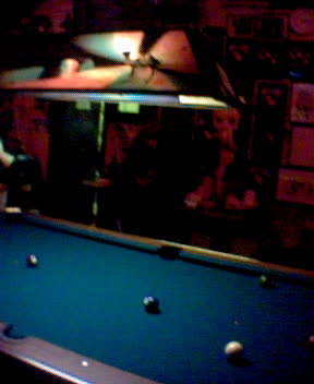 man is playing pool at the bar in the dark