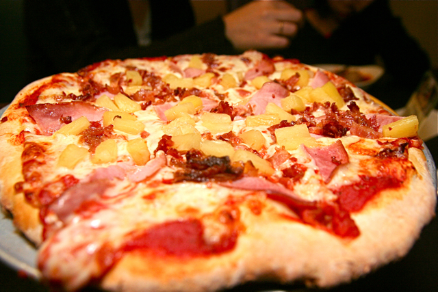 a small pizza has pineapple and ham toppings