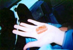 the person is sitting and holding out their hand to a finger with the orange lipstick on it