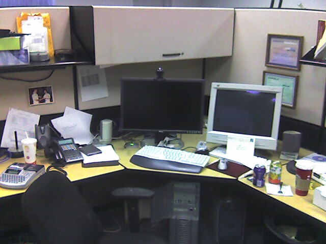 an office cubicle with multiple monitors and laptops
