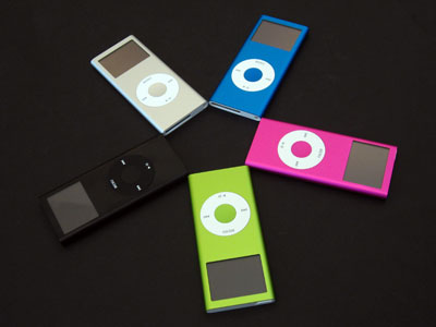 four colored ipods on a black surface