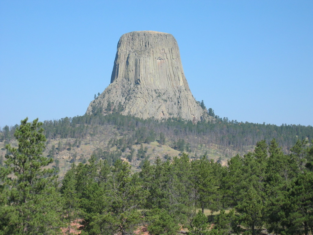 the view of a large rock, from behind some trees