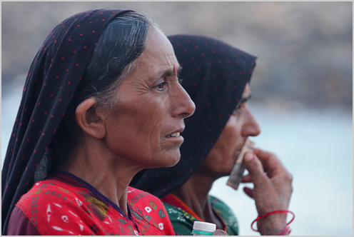 two women wearing headscarves, looking off in distance