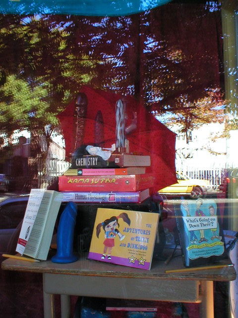 a shelf with many books on it, sitting under a tree