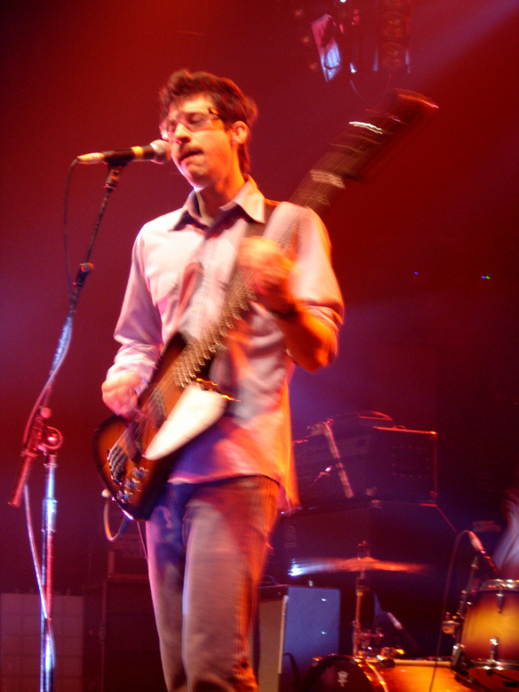 a young man holding a guitar on stage with a microphone