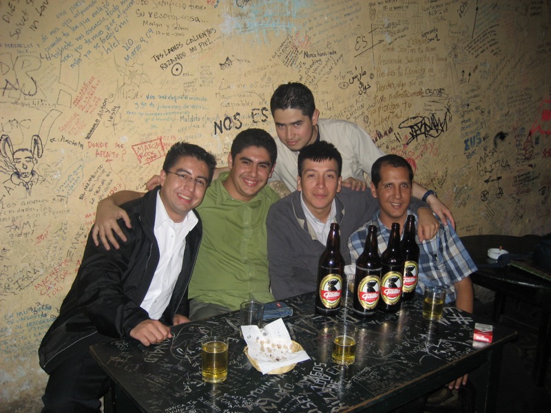 four men in a room with several beers