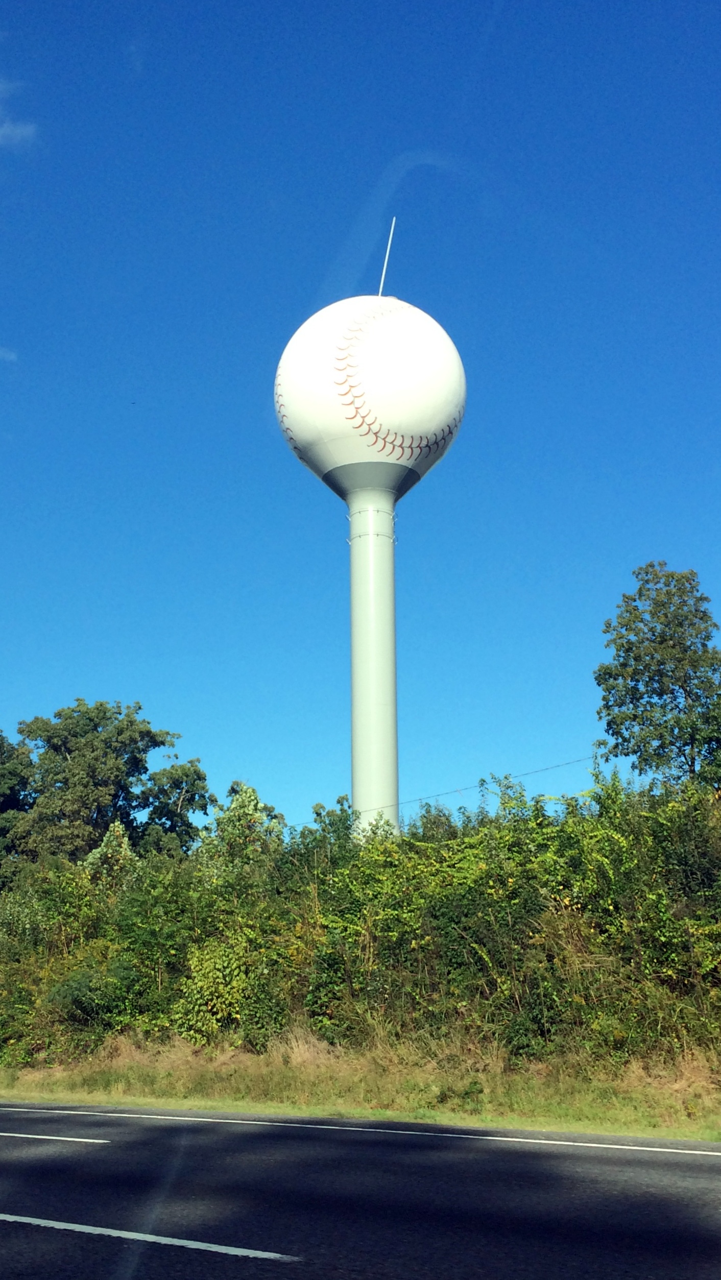 a baseball cap shaped building on the side of a highway