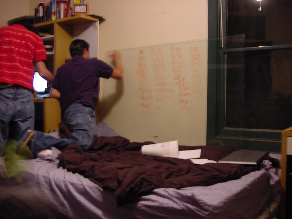 two men are jumping off a bed with purple sheets