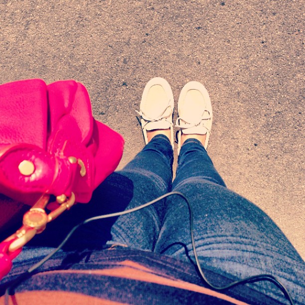 a woman is wearing white shoes and a red purse