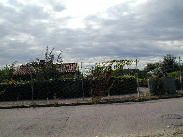 a fence with a house and a tennis court next to it