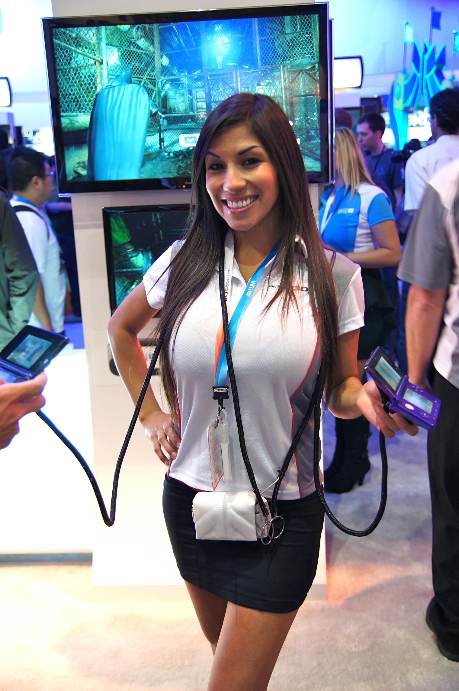 the young woman is standing next to an enormous monitor
