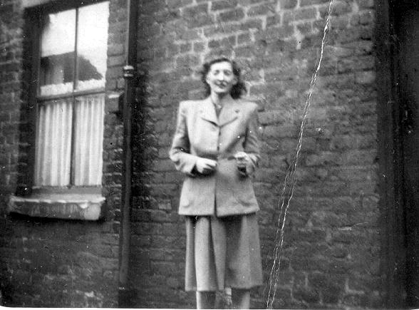 woman in coat and slacks standing on city street