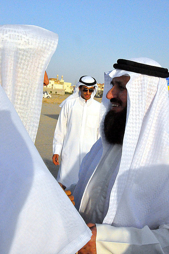 men wearing white clothes talking while onlookers look on