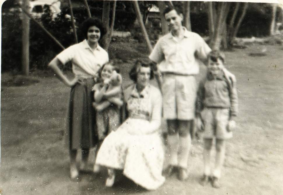 an old po shows a woman standing and two men and two children in dresses