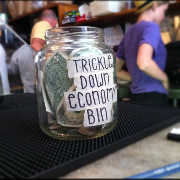 a mason jar sitting on a counter with someone putting money in it