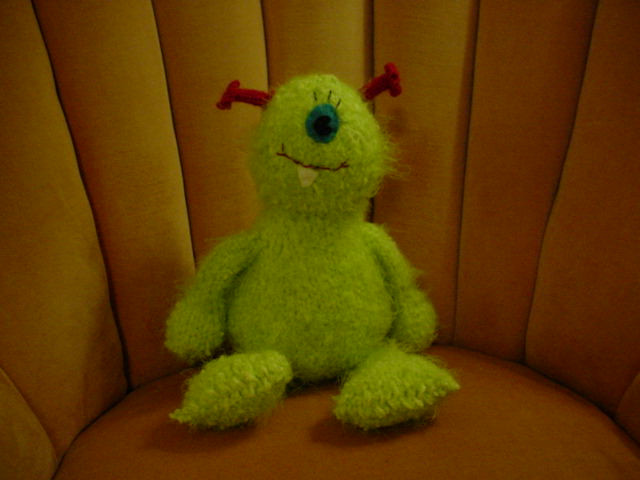 a green toy sitting on top of a couch
