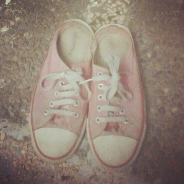 pink shoes on top of a floor with a broken shoelace