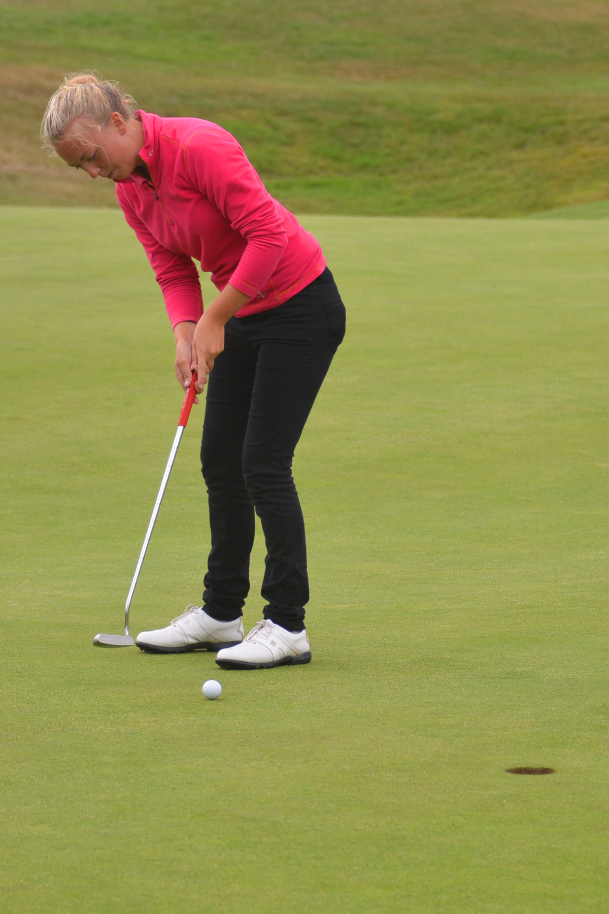 a woman is putting a ball onto the green