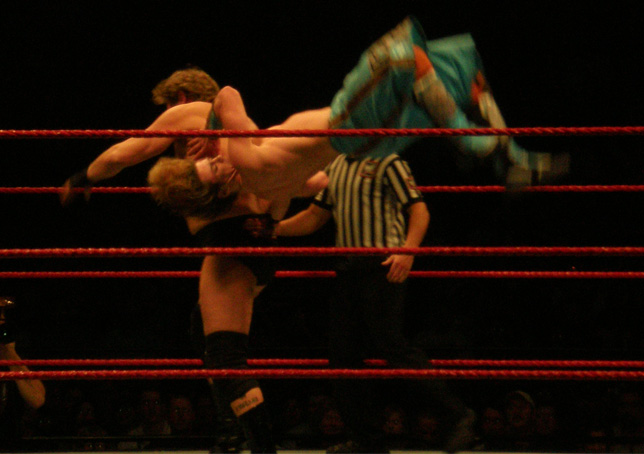 two men wrestling in an arena during a game