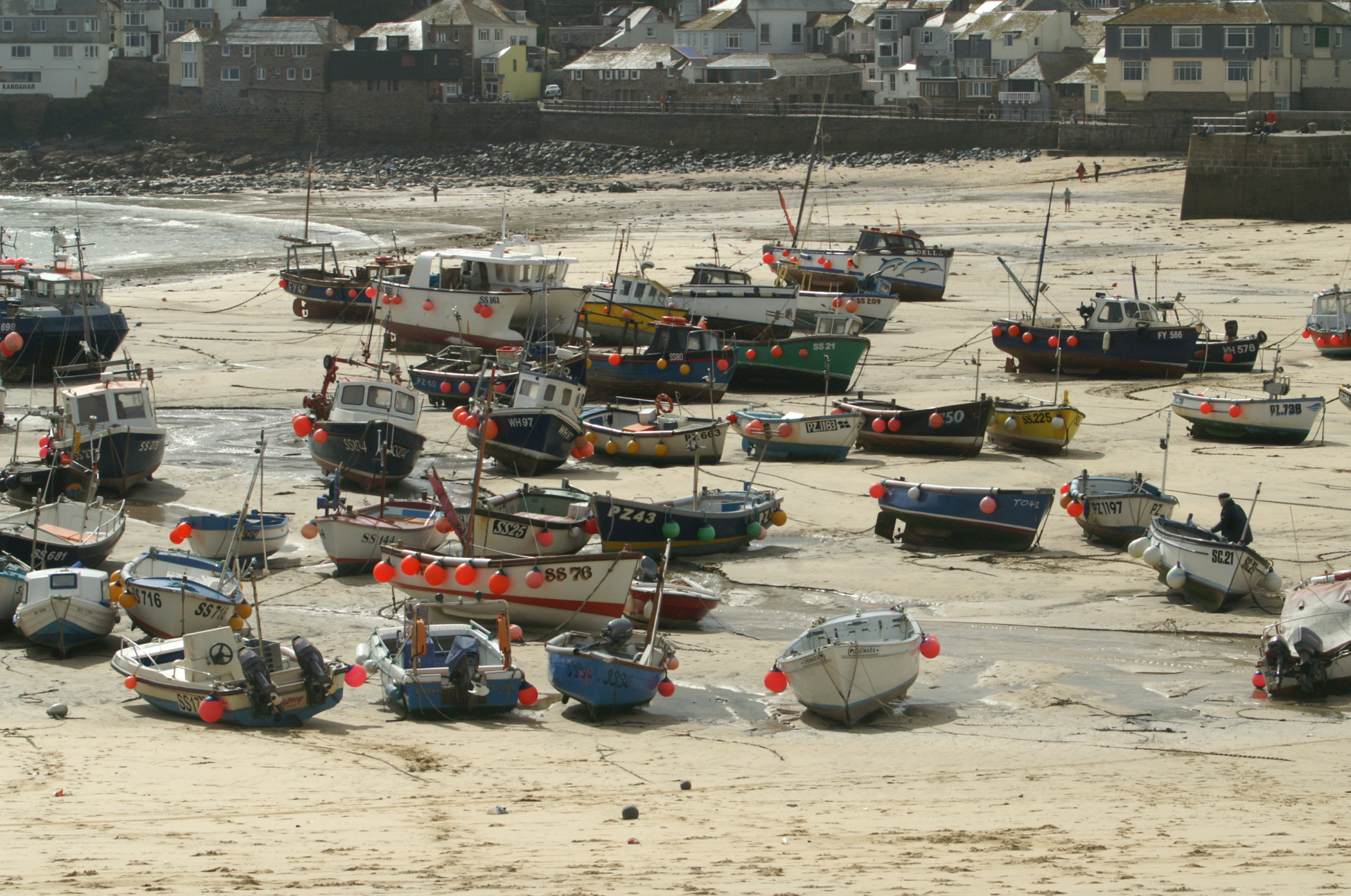 many boats on the sand near buildings