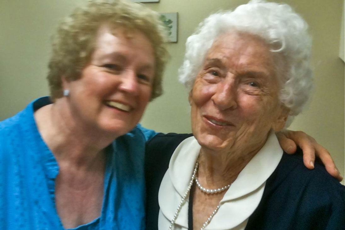 an older woman standing next to another women who is holding her arm around her neck