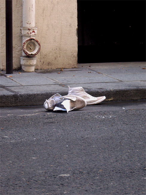 a discarded white sneakers lies on a corner
