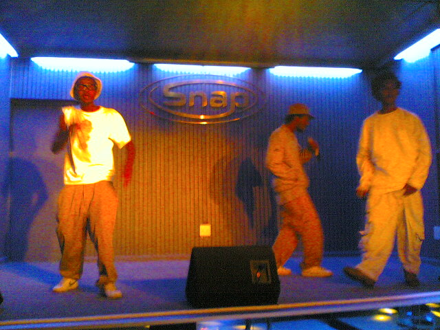 several guys are standing on a stage and one is singing