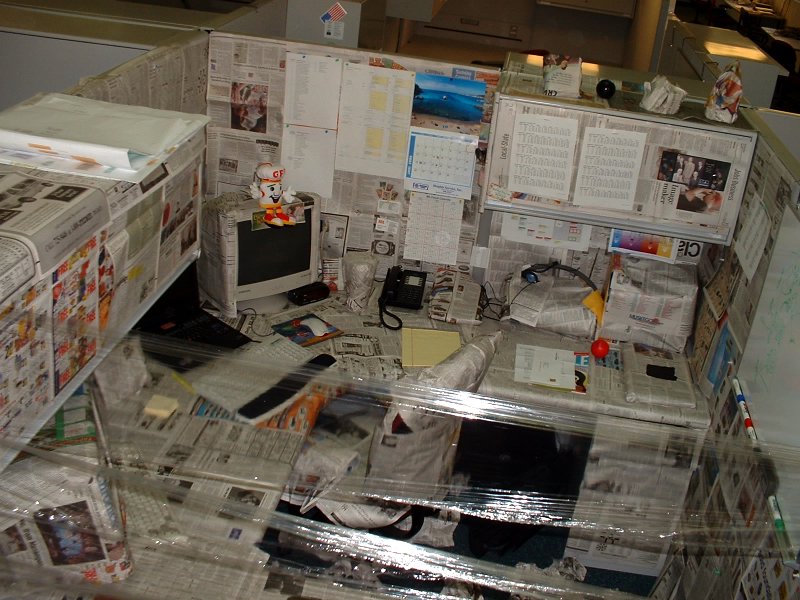 a desk covered in a pile of paper next to a phone