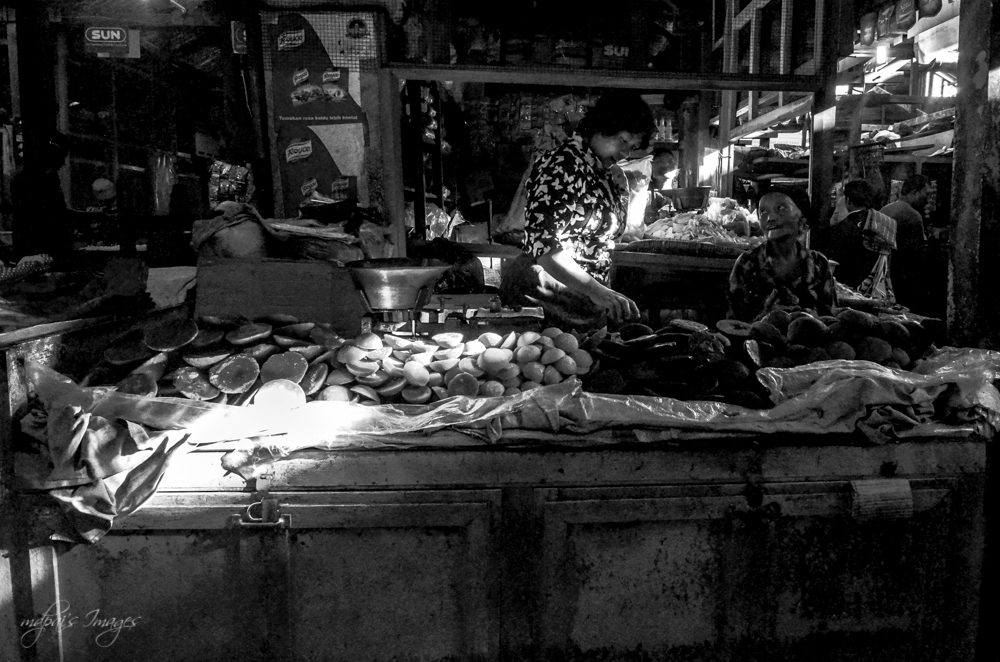 some people sitting at tables and bags in a market