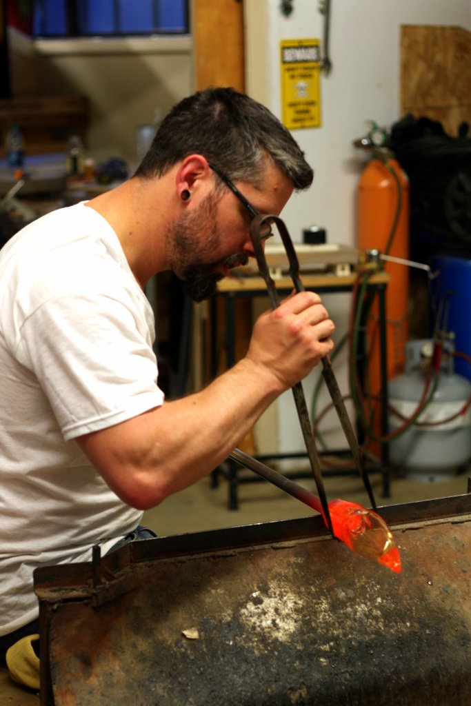man in glasses working on an object with a large metal tube