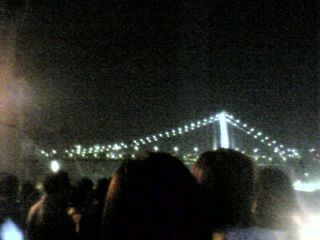a crowd of people standing in front of a bridge at night