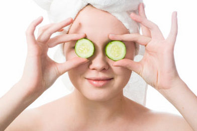 a girl with a towel over her head holding two cucumbers on their eyes