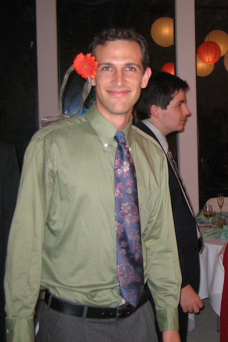 a man wearing a tie, and a flower pinned to his head