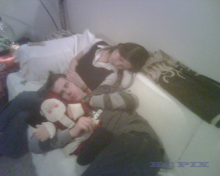 a man and woman laying in a bed with a stuffed animal