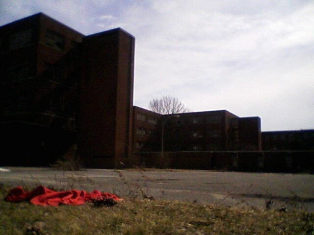 a red piece of cloth sits in front of an abandoned building