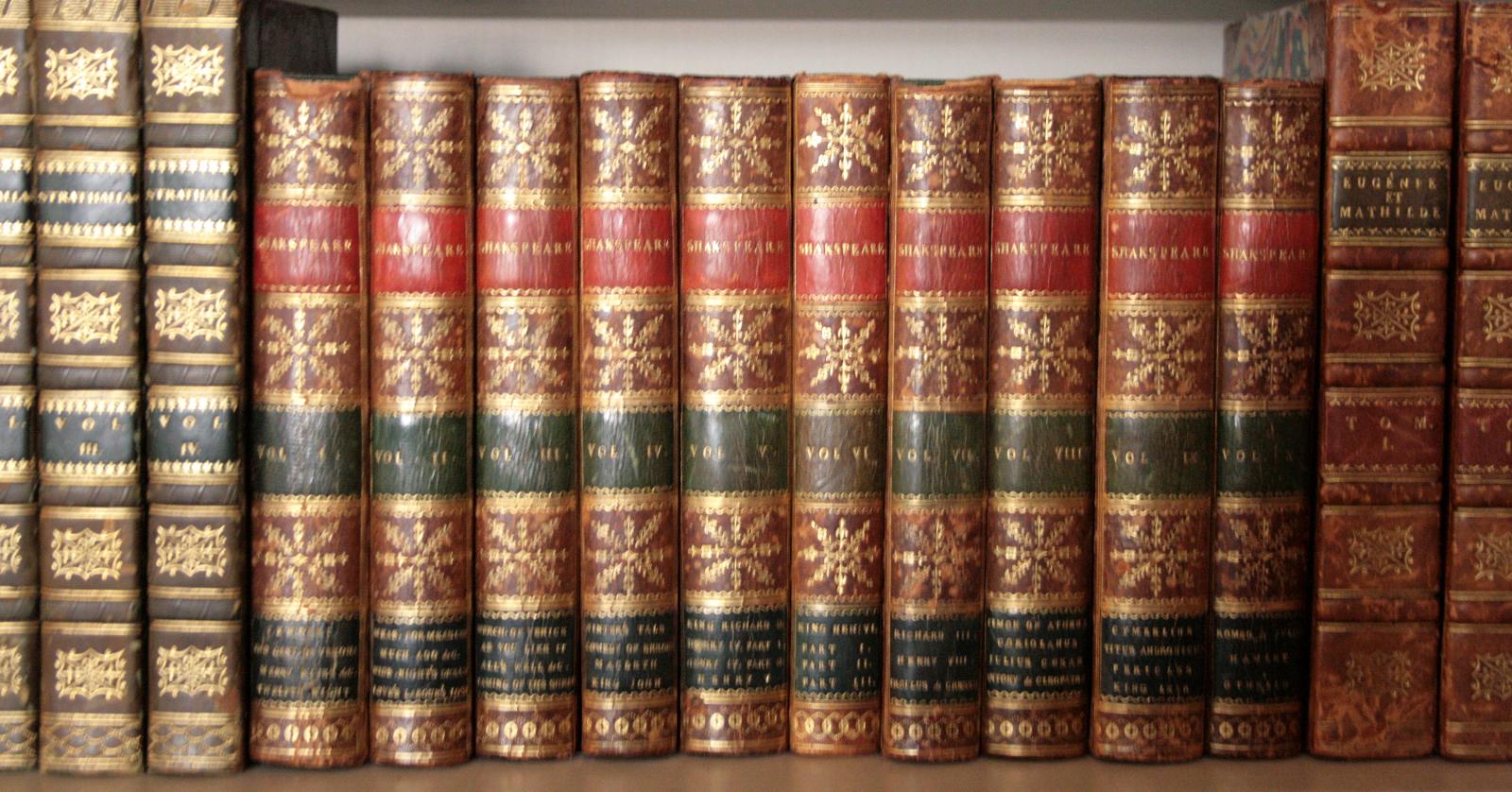 a stack of books on top of a wooden shelf